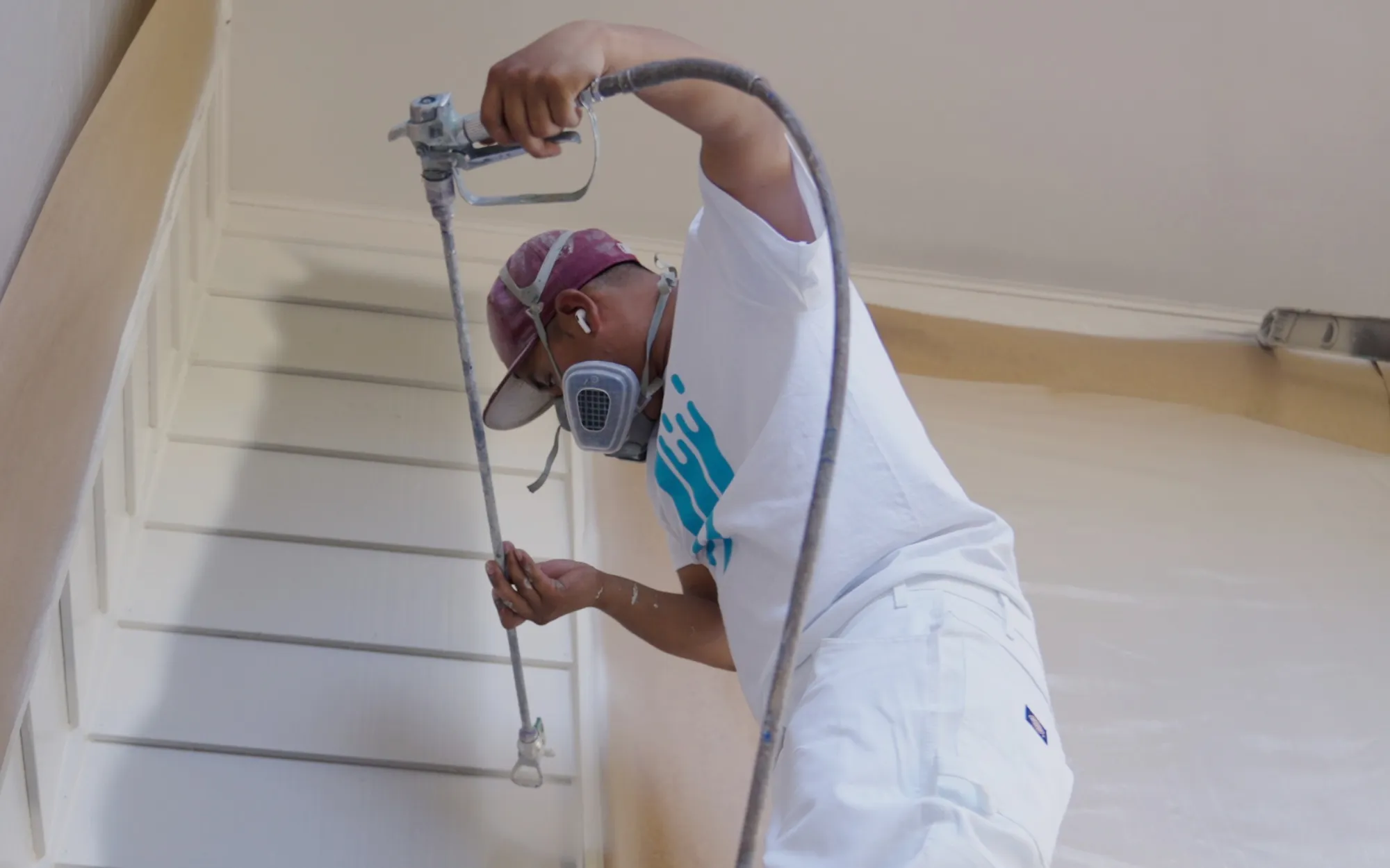 That 1 Painter crew member spray-painting exterior trim with precision