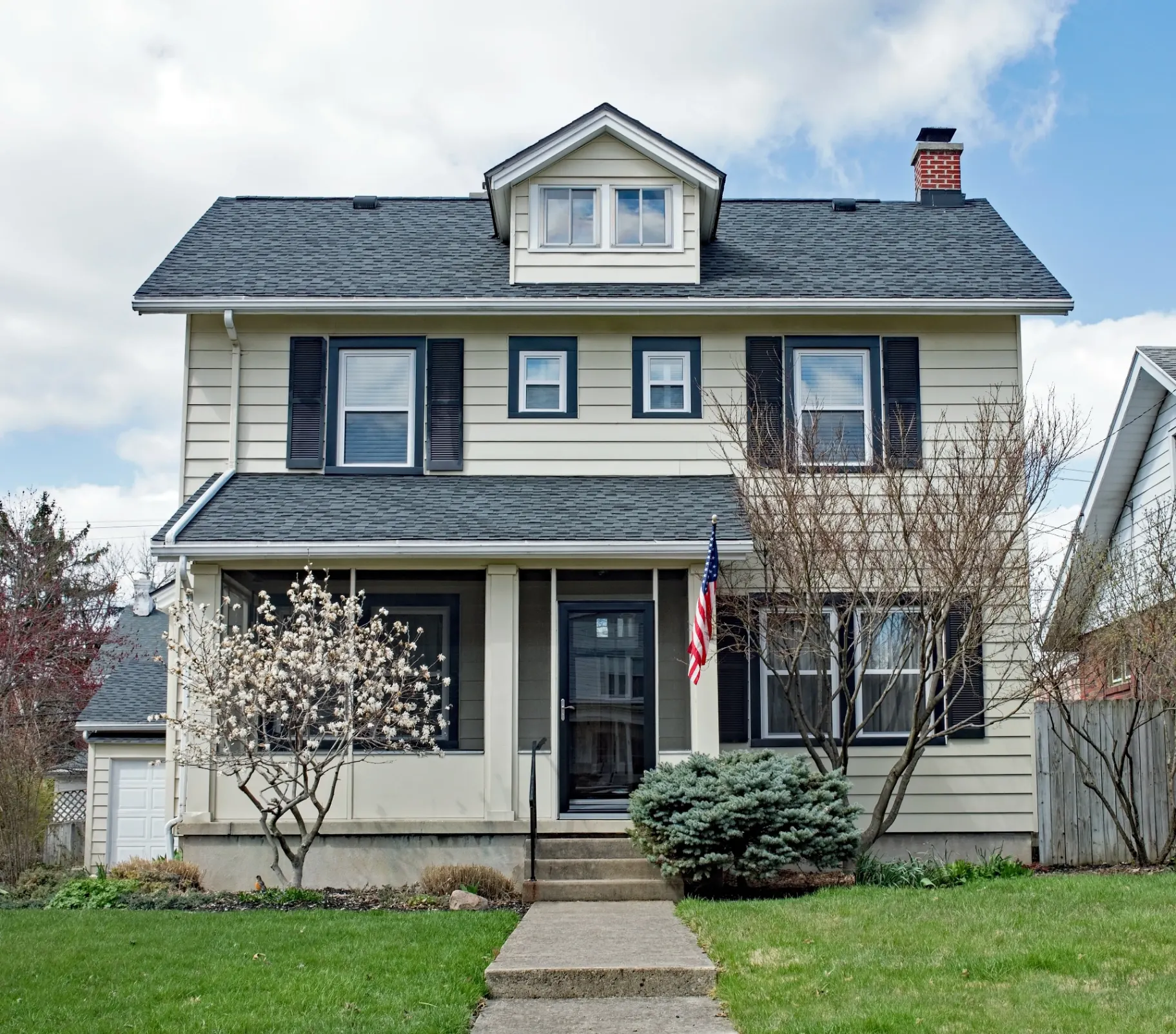 Classic colonial home exterior with warm cream siding and dark shutters professionally repainted by That 1 Painter