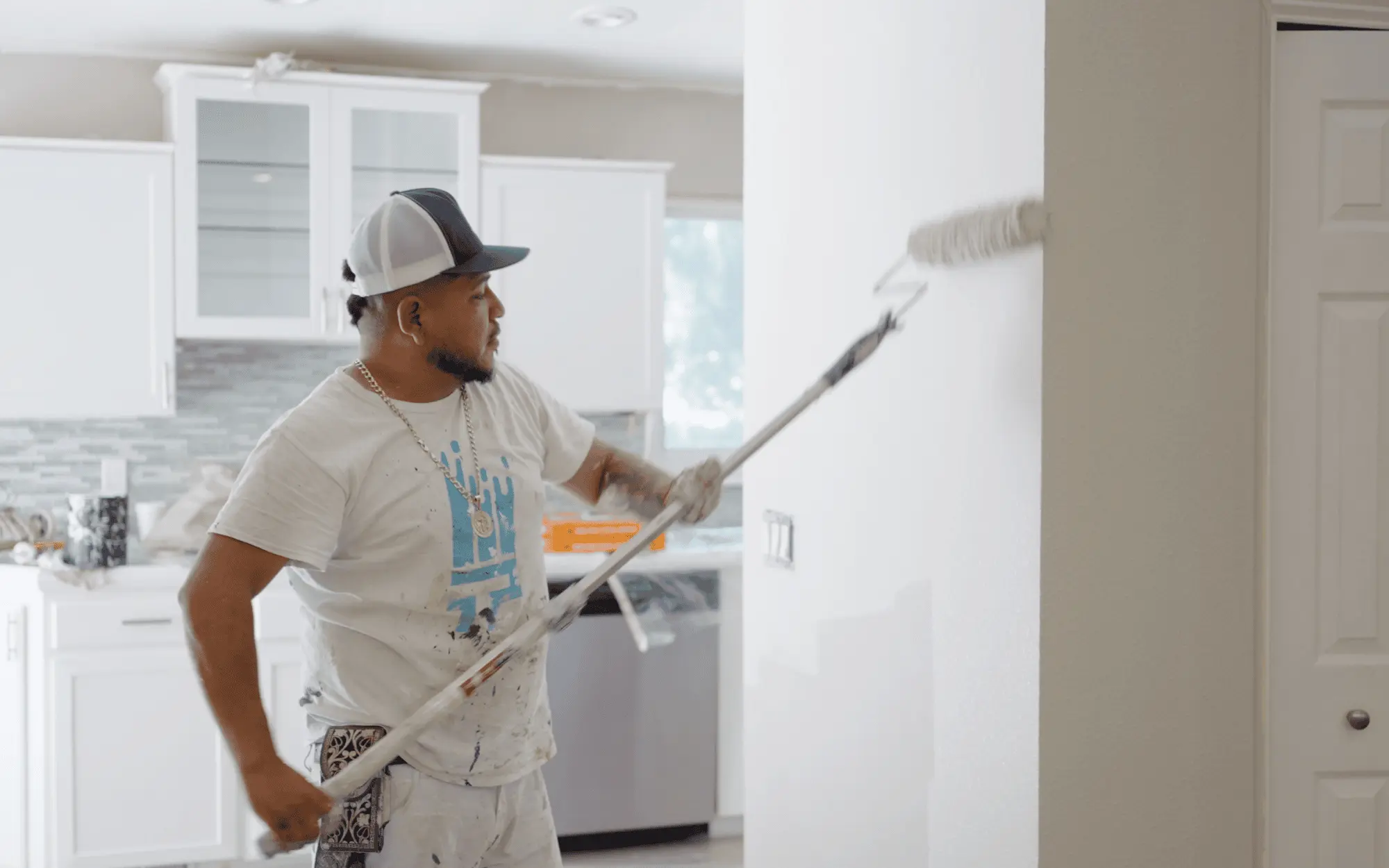 Professional interior painting in progress, painter rolling fresh paint on a living room wall in a modern home
