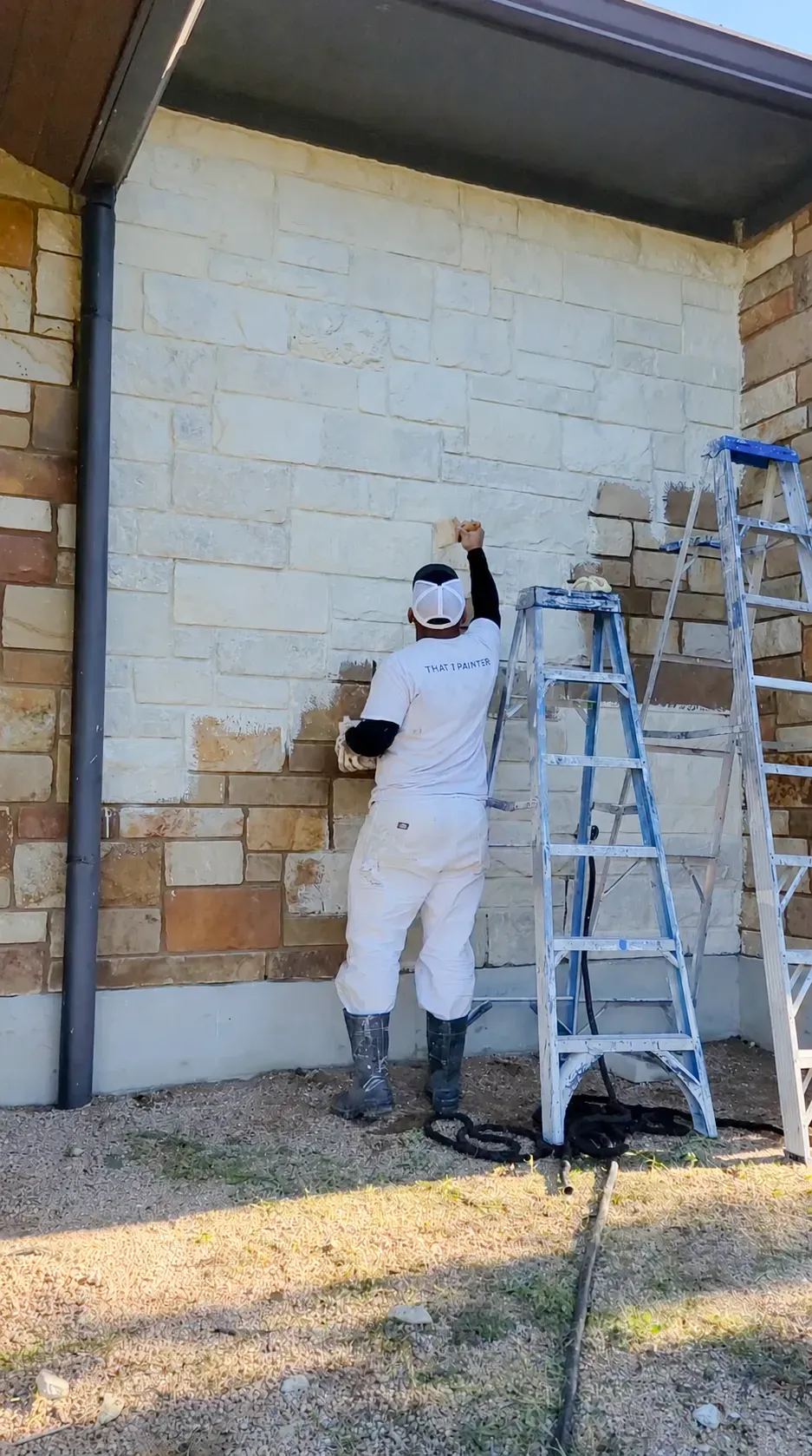 Painter applying limewash to misted brick exterior in layered, wet-on-wet brushwork