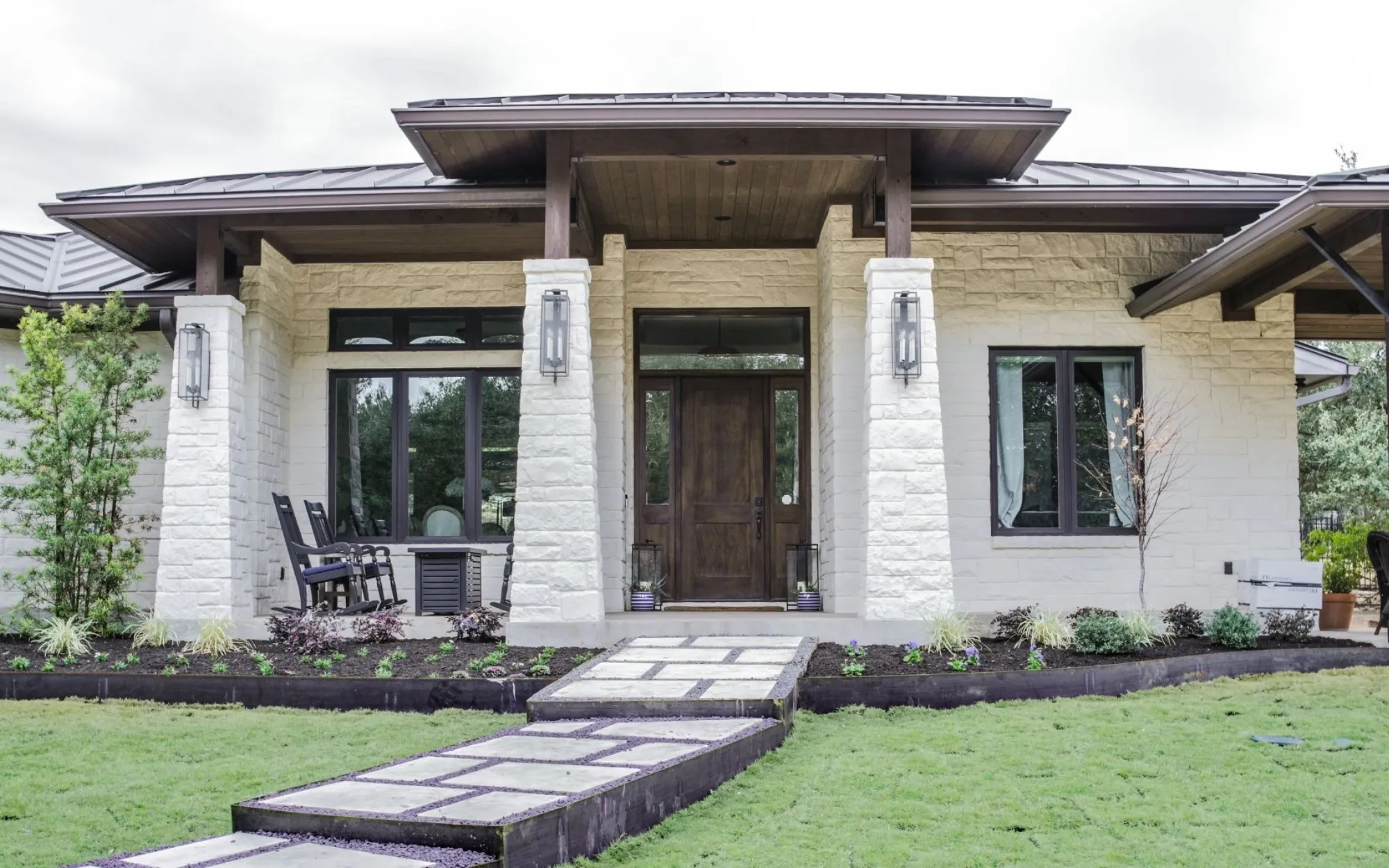Hill country limewashed stone home with wood entry and metal roof