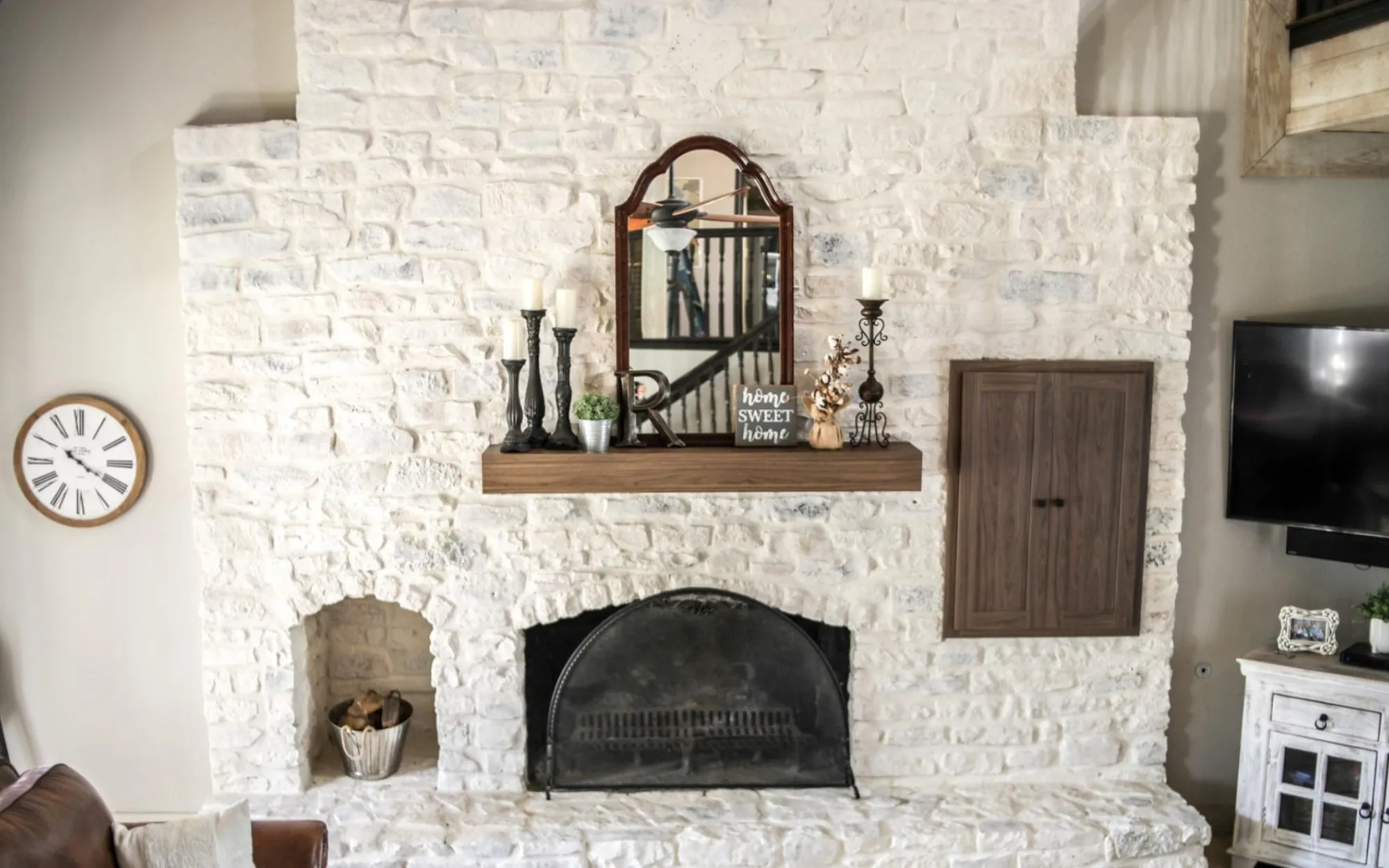 Interior limewashed stone fireplace with mantel and decor