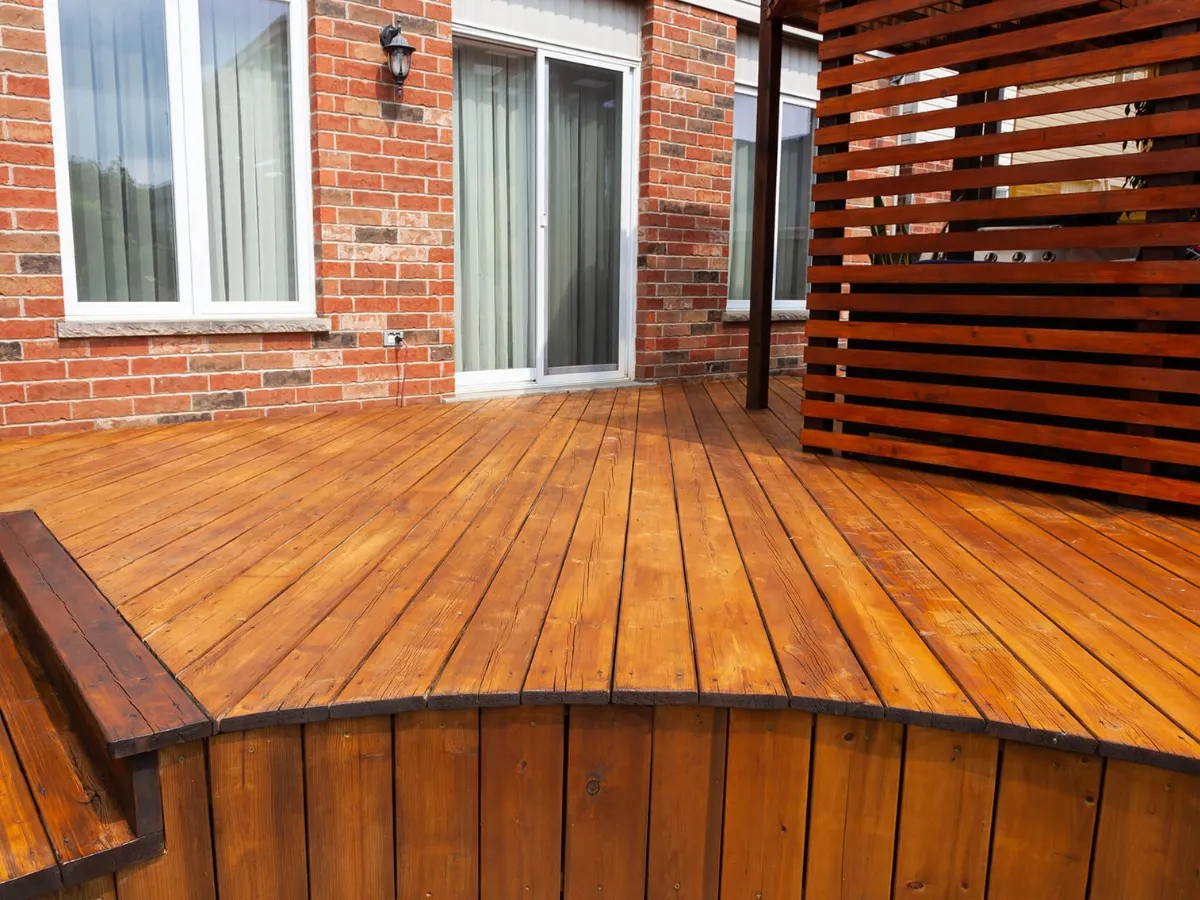 Backyard wood deck freshly stained in warm cedar tone with built-in bench