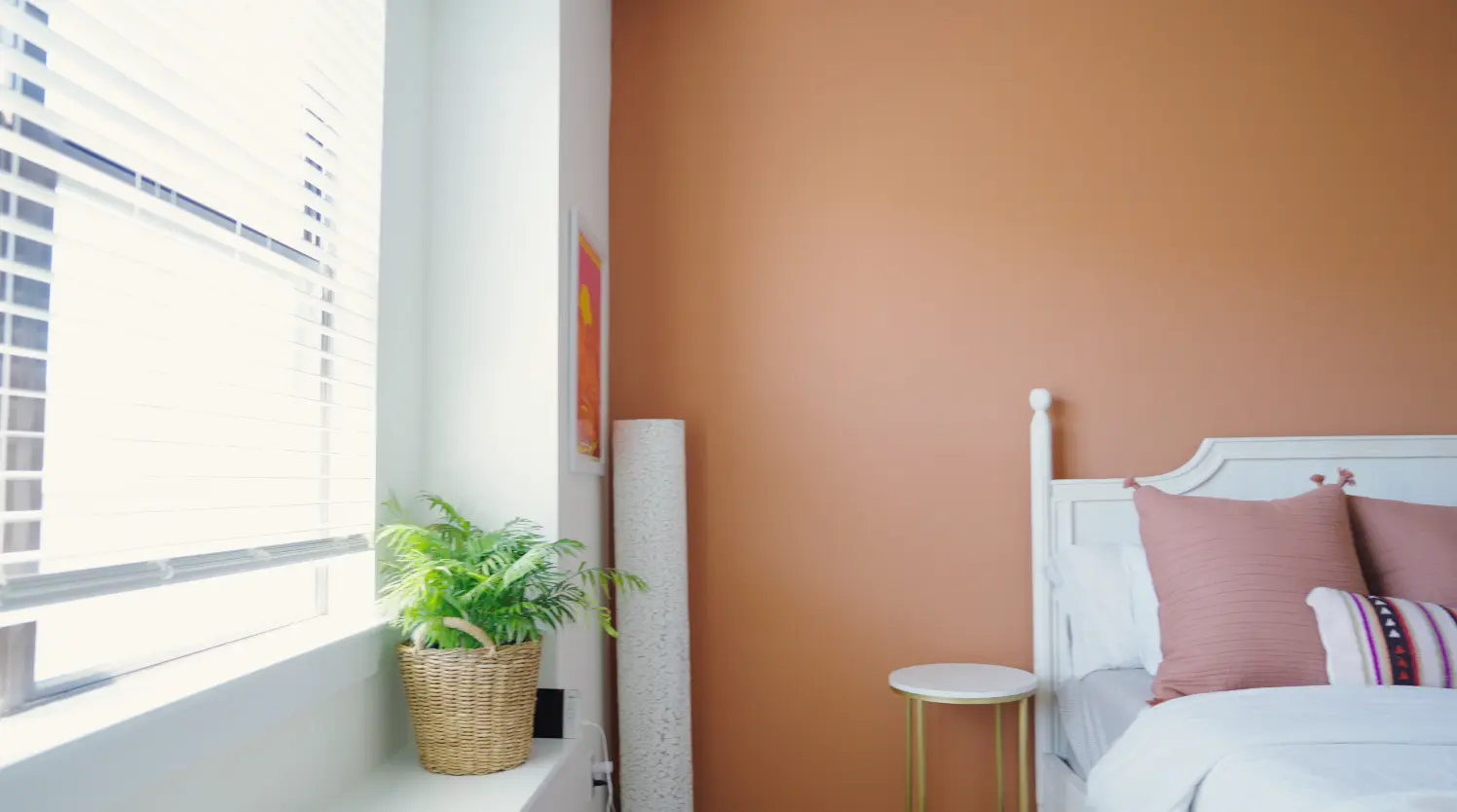 Bedroom with a freshly painted terracotta accent wall and crisp white trim after a repair and touch-up visit