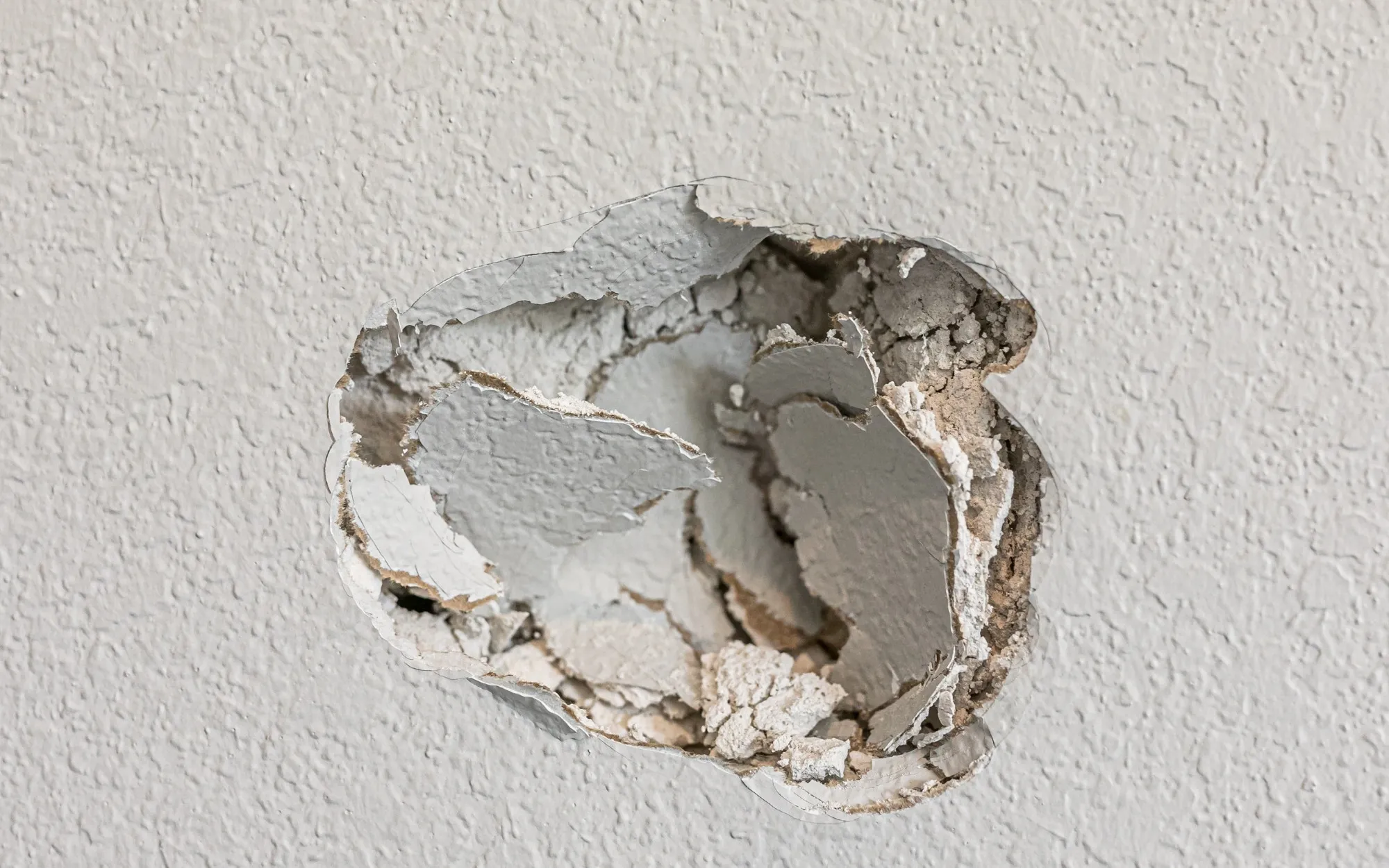 Hole in textured drywall ready for patching and priming