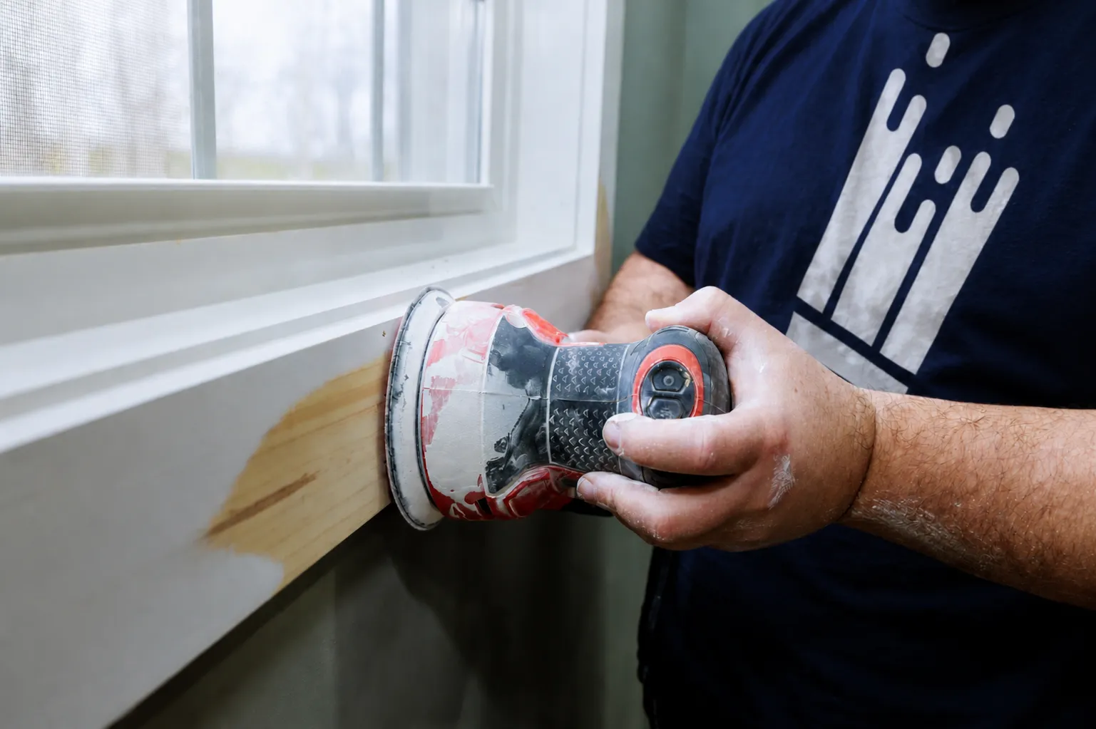 Painter sanding window trim during a home repair and maintenance visit