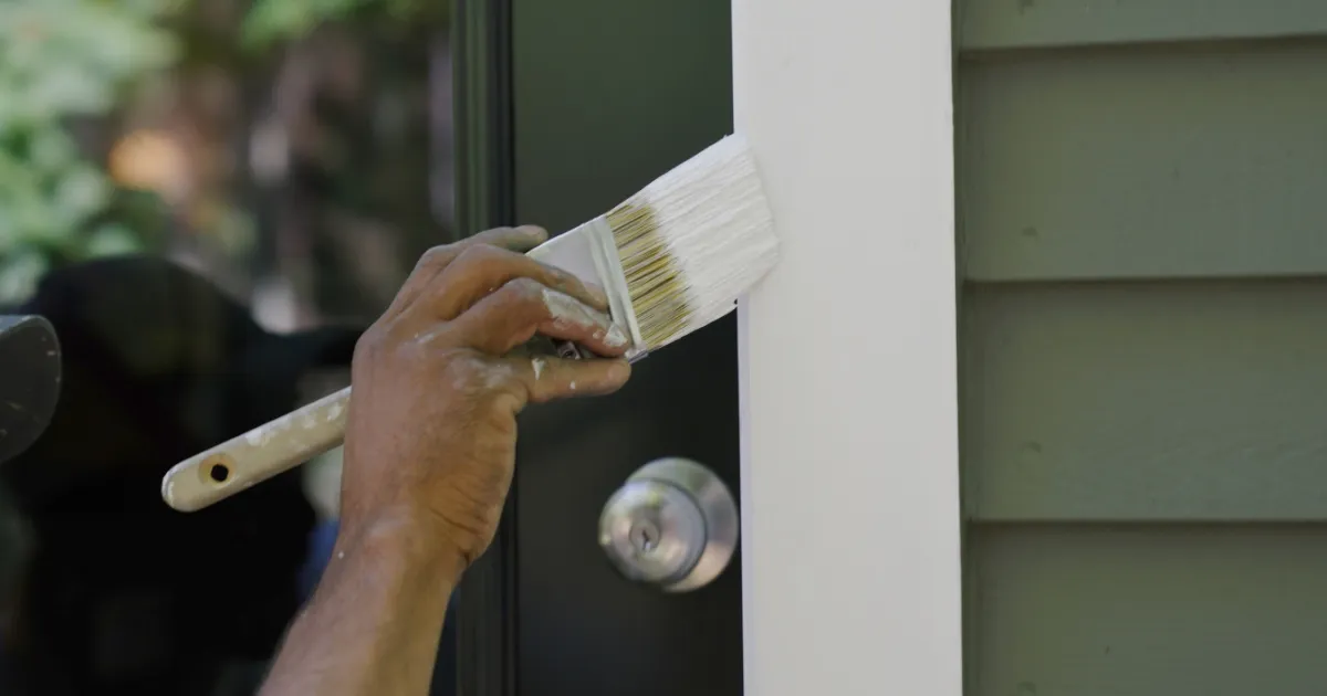 Painter touching up an exterior door trim with a brush before listing photos